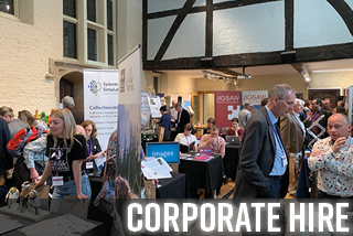 A conference is taking place with different stalls in the Tudor Hall and visitors milling around them